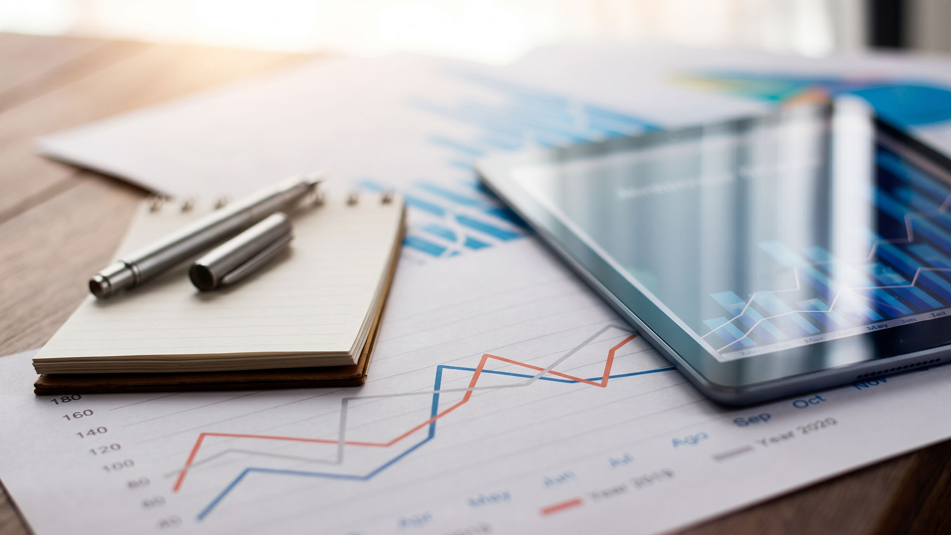 Grafici finanziari, tablet e registri contabili per il calcolo delle liquidazioni IVA periodiche aziendali.